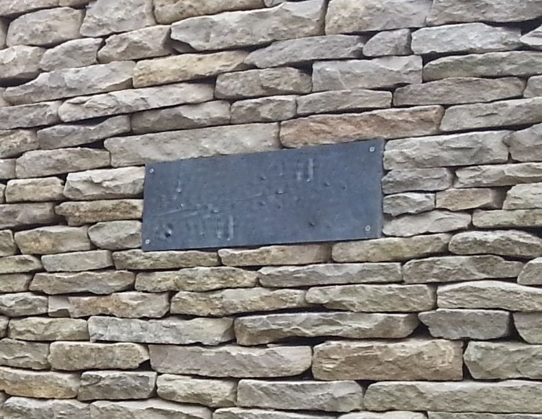 A slate house nameplate in a dry stone wall